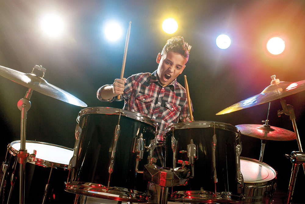 Das Bild der Musikschule Odenwald zeigt einen Jungen am Schlagzeug mit Rampenlicht im Hintergrund